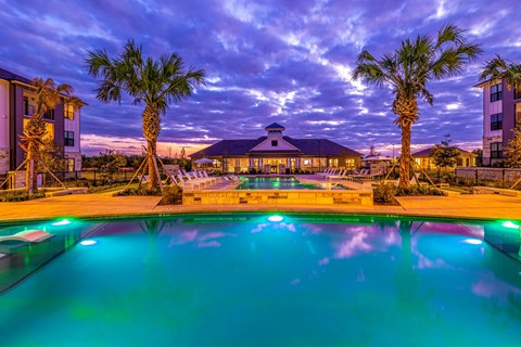 a swimming pool with palm trees and a building in the background